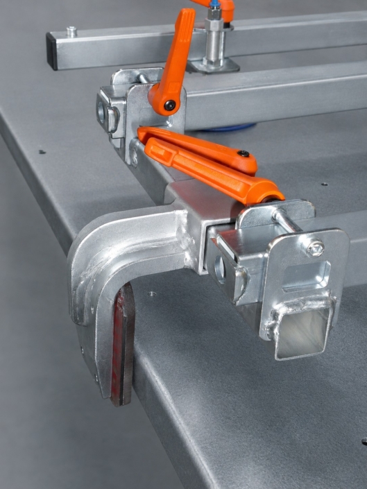 blechgreifer-detailaufnahme-spannhebel-an-blechtafel Detailaufnahme eines Blechgreifers mit orangefarbenen Spannhebeln zur sicheren Fixierung einer Blechtafel.