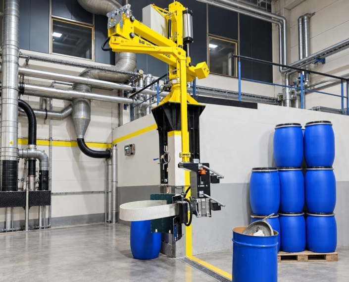 Fassmanipulator mit Fassgreifer zur sicheren Handhabung und Positionierung blauer Kunststofffässer in einer industriellen Produktionsanlage.