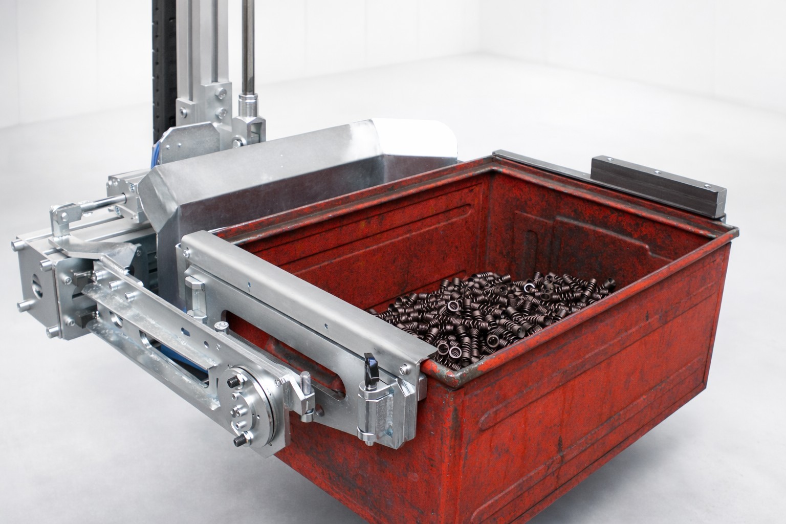 lastaufnahmemittel-kastengreifer-schwerlastkasten-teilehandling Lastaufnahmemittel Kastengreifer zum sicheren Greifen und Transportieren eines gefüllten Schwerlastkastens mit Metallteilen in der industriellen Fertigung