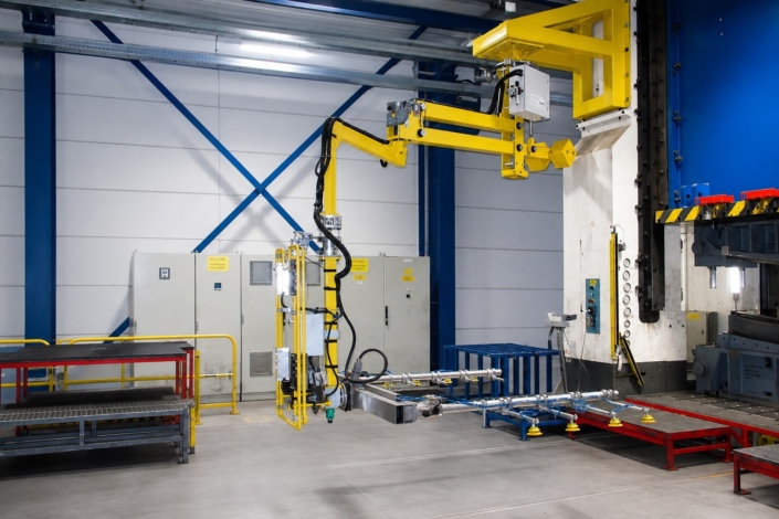 Vakuumsauger Bleche an einem gelben Schwenkarm-Manipulator mit Saugrahmen für das präzise Handling von Bauteilen an einer Industrieanlage.