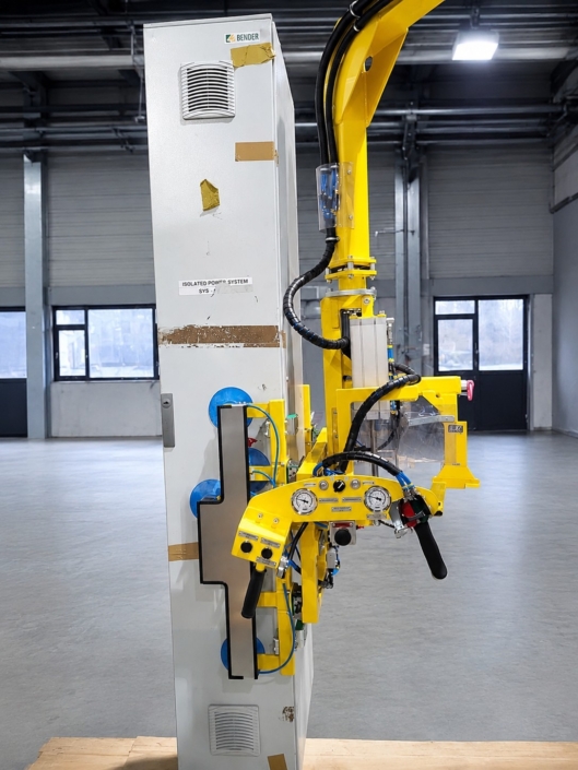 Vakuumsauger Bleche an einem gelben Vakuumheber halten ein hohes Schrankgehäuse mit blauen Saugnäpfen für das sichere Positionieren in der Industriehalle.